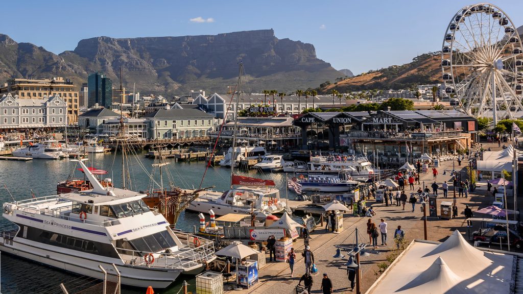 Yachts in harbour at waterfront with ferris wheel and mountain backdrop